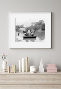 Photo: Group of men on raft, river, trees and shrubbery, one man standing on shore
