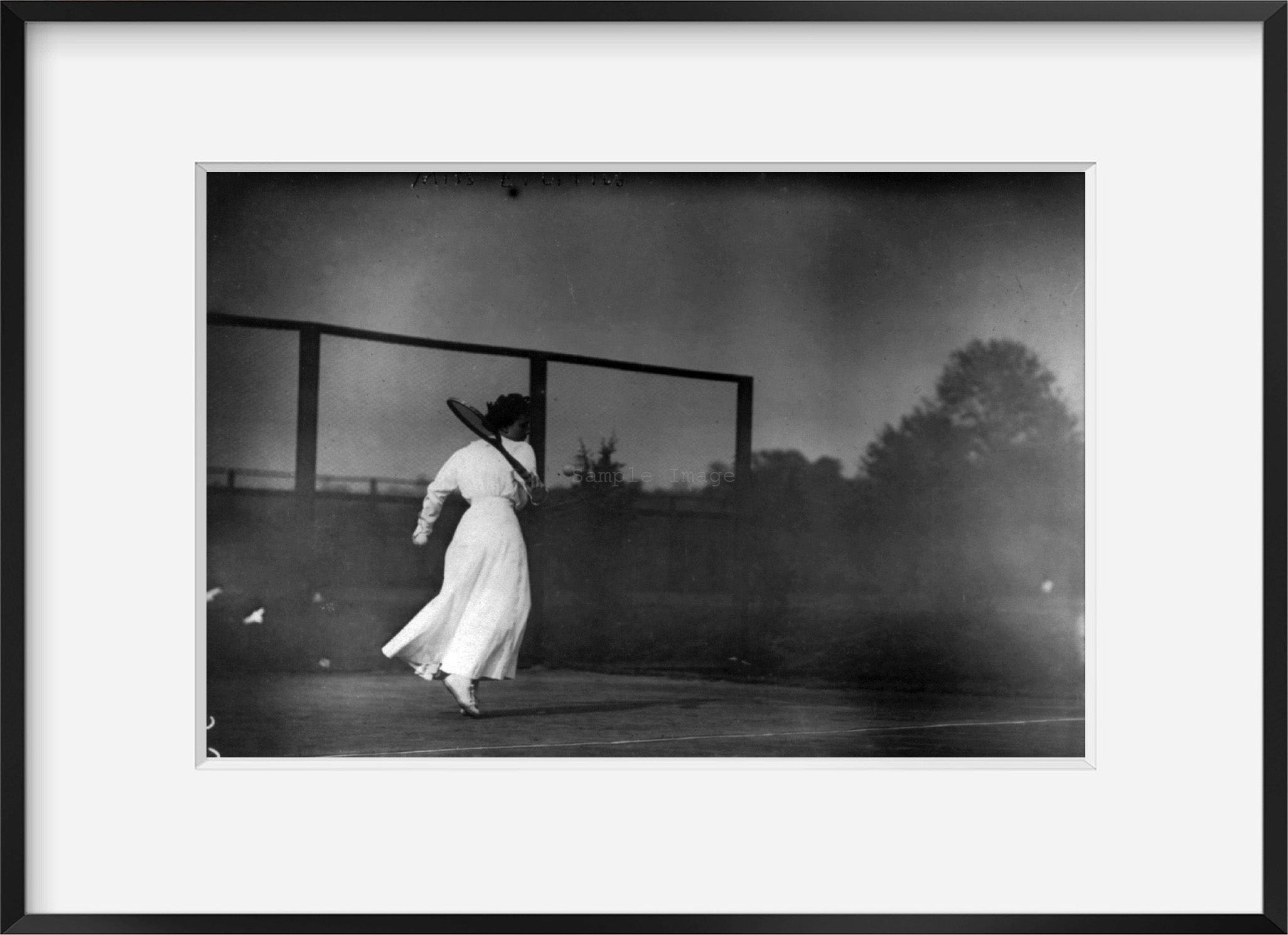 Photo: Miss E. Little, swinging at tennis ball, February 1912, wearing white dress